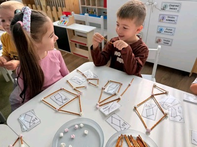 Copii construind forme geometrice din bețe și marshmallow