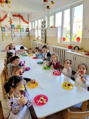 Copii pregătind frigărui de fructe în sala de mese