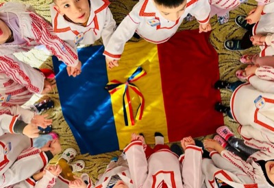 Copii în jurul tricolorului în costume populare