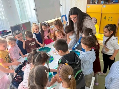 Educatoare și copii pictând Pământul